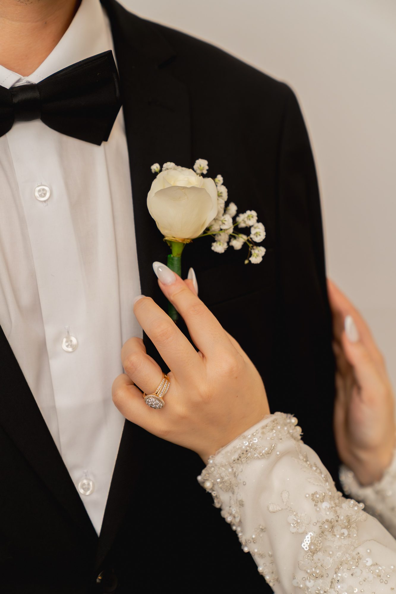 Bride holding a white rose boutonniere in quiet getting ready light