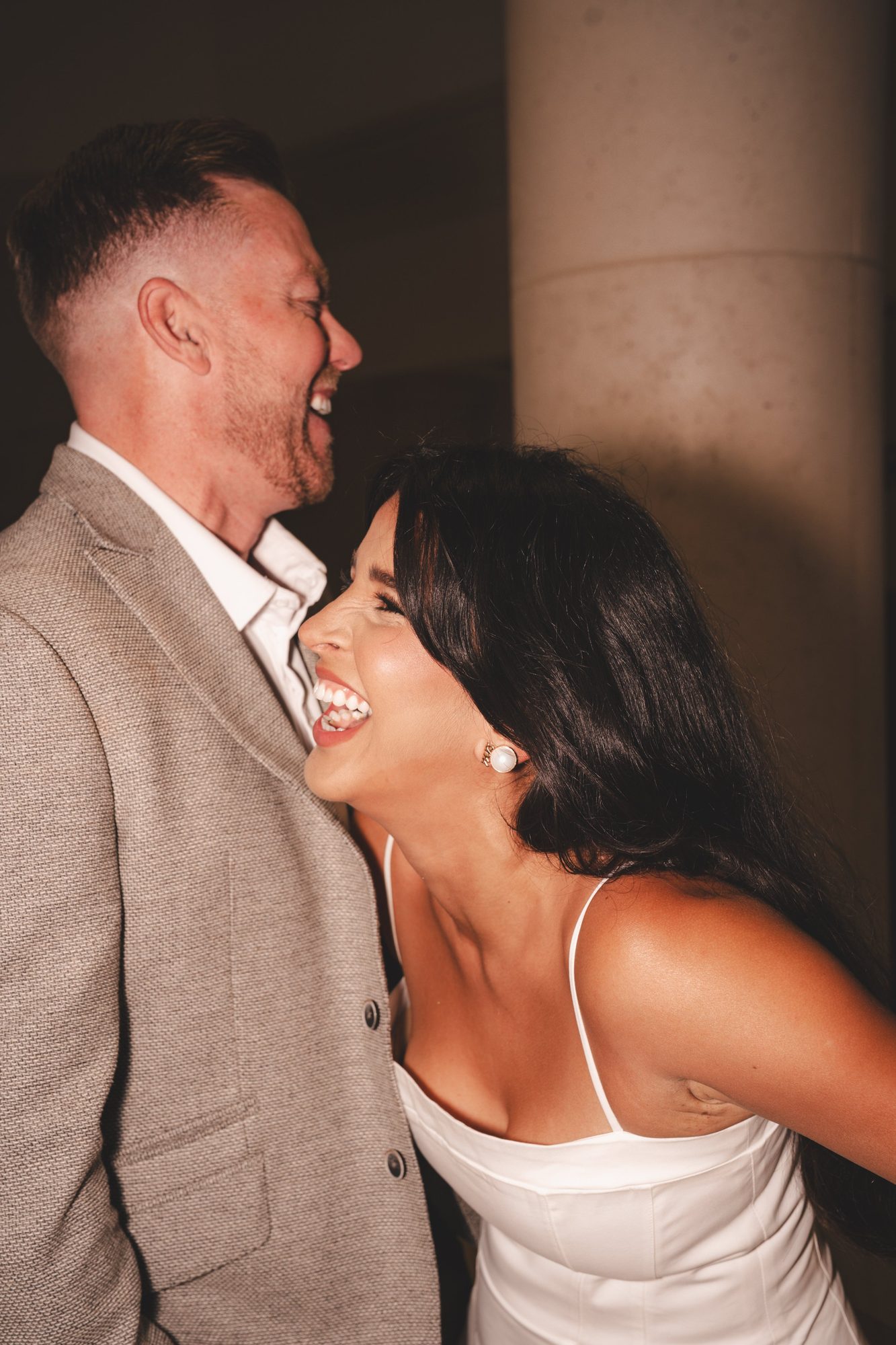 Couple laughing together near a stone column during portrait time