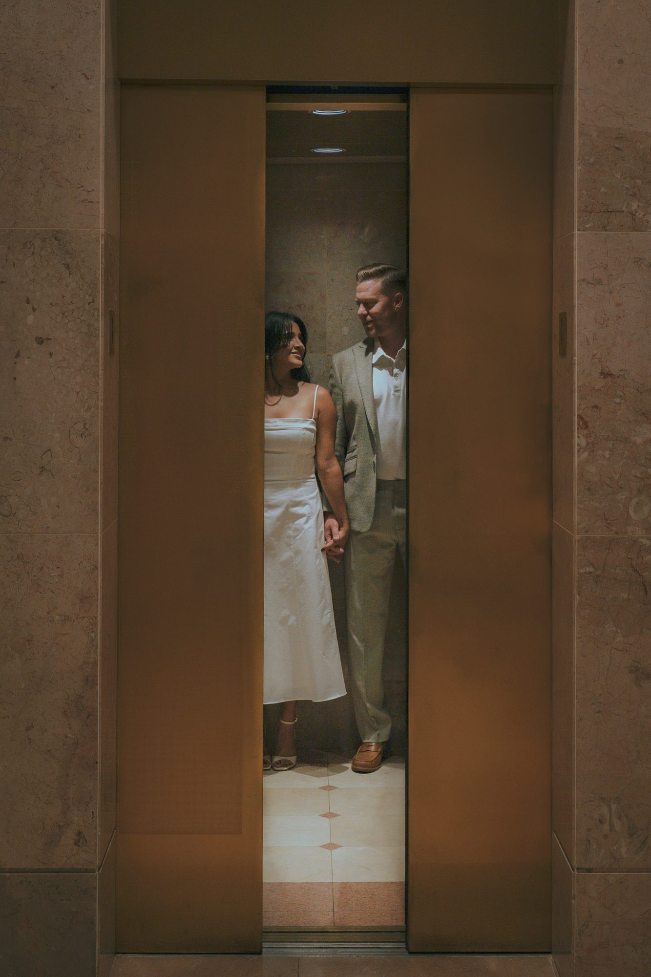 Couple holding hands framed by parting elevator doors