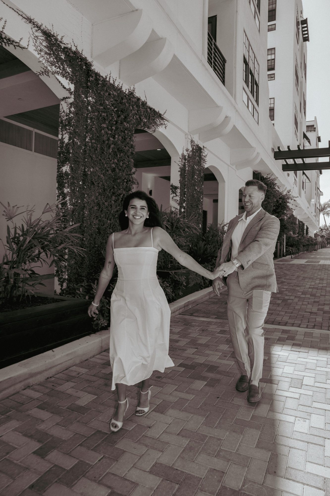 Couple laughing together near a coastal archway in soft light