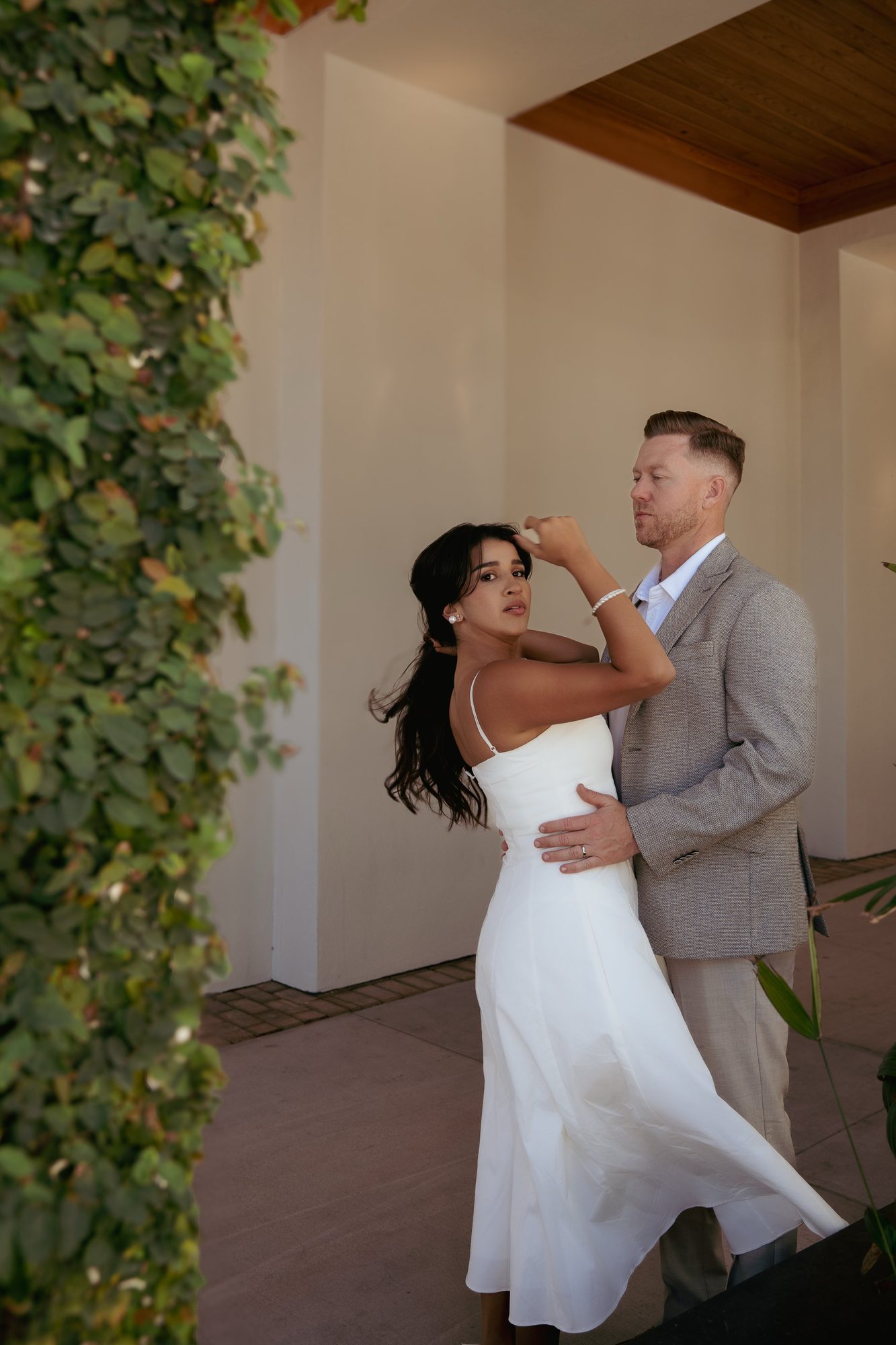 Couple embracing under a covered walkway before their outdoor ceremony