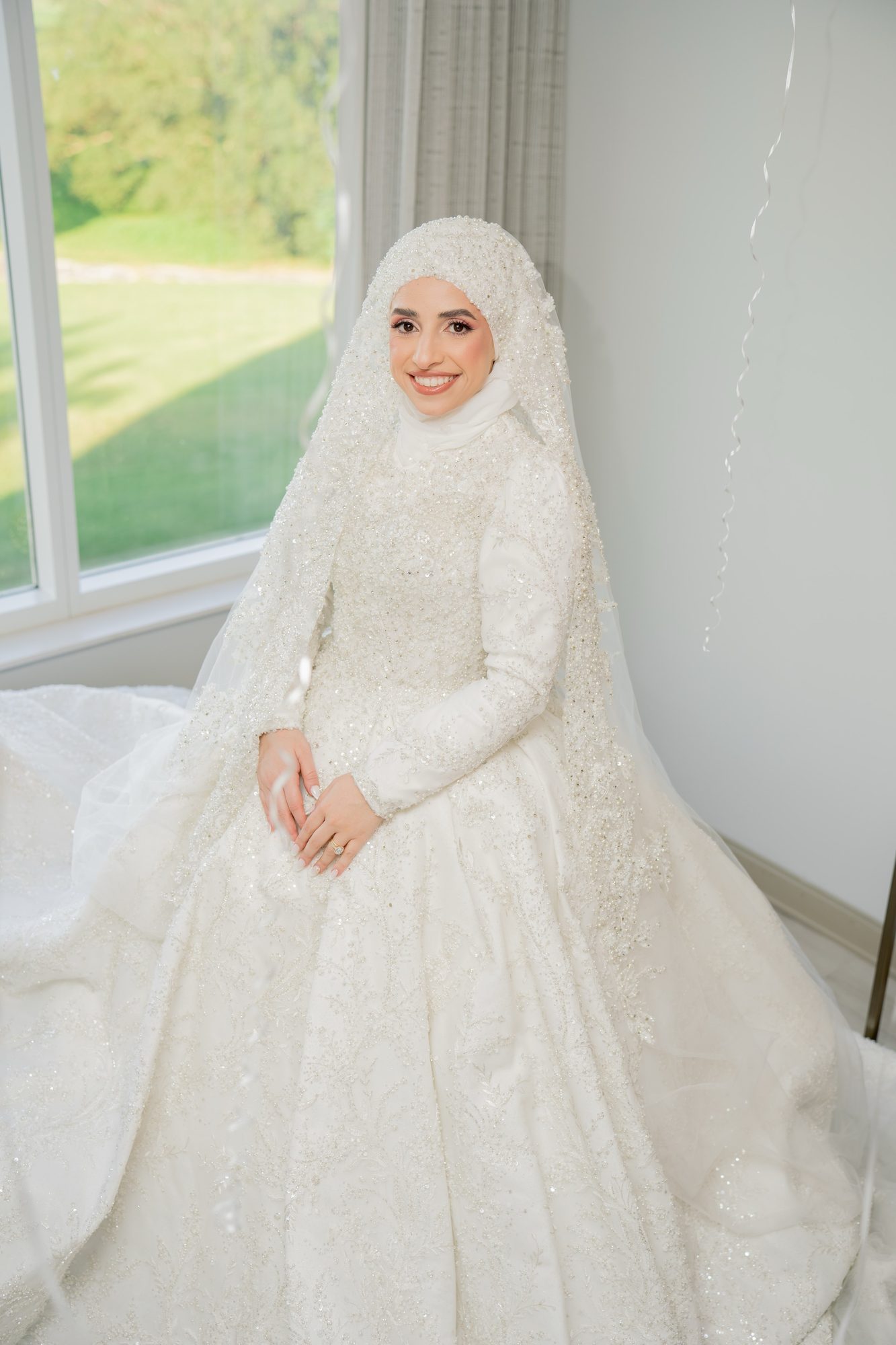 Bride seated by a window in soft wedding morning light
