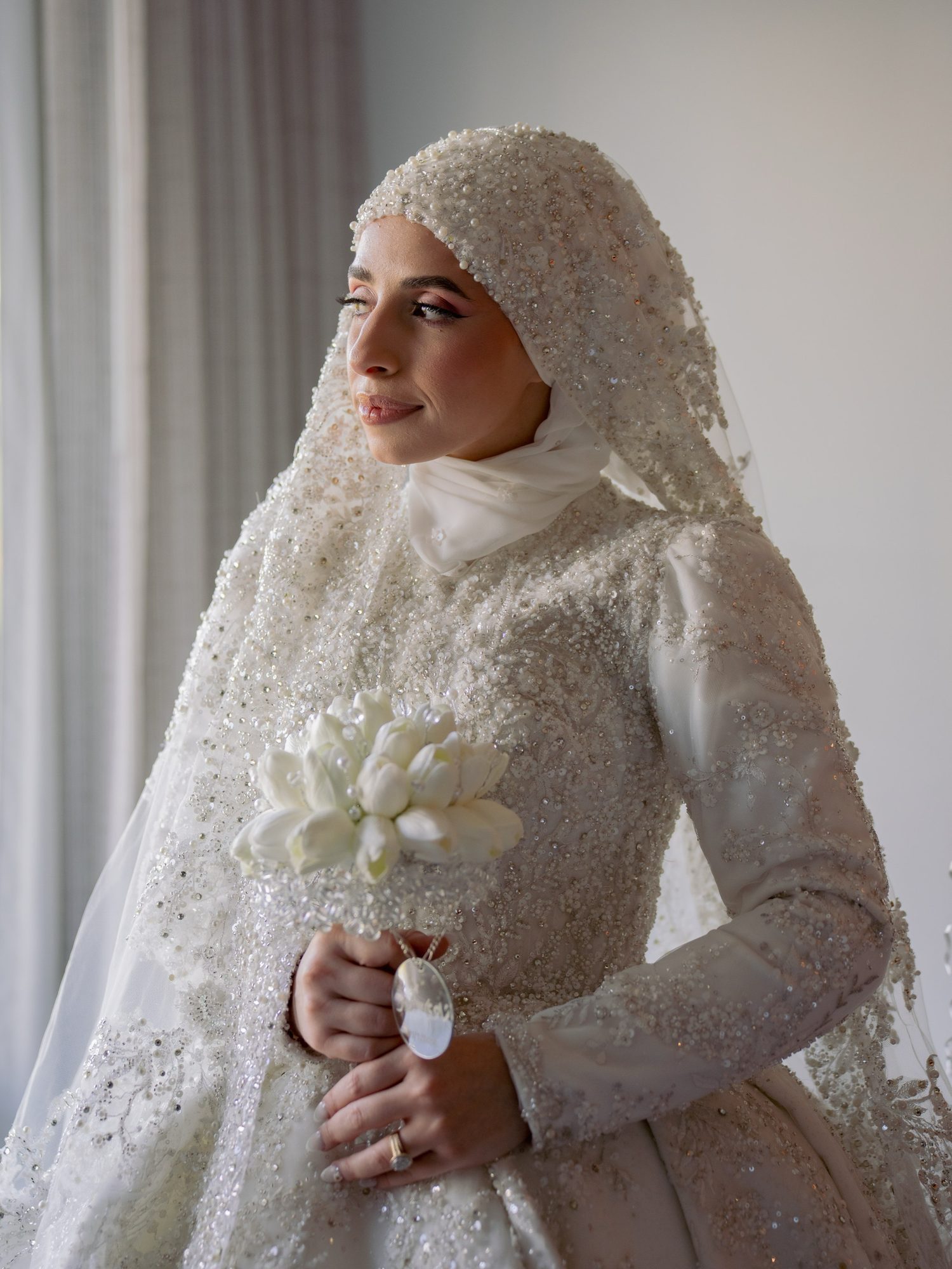 Bride holding a bouquet beside soft window light before the ceremony