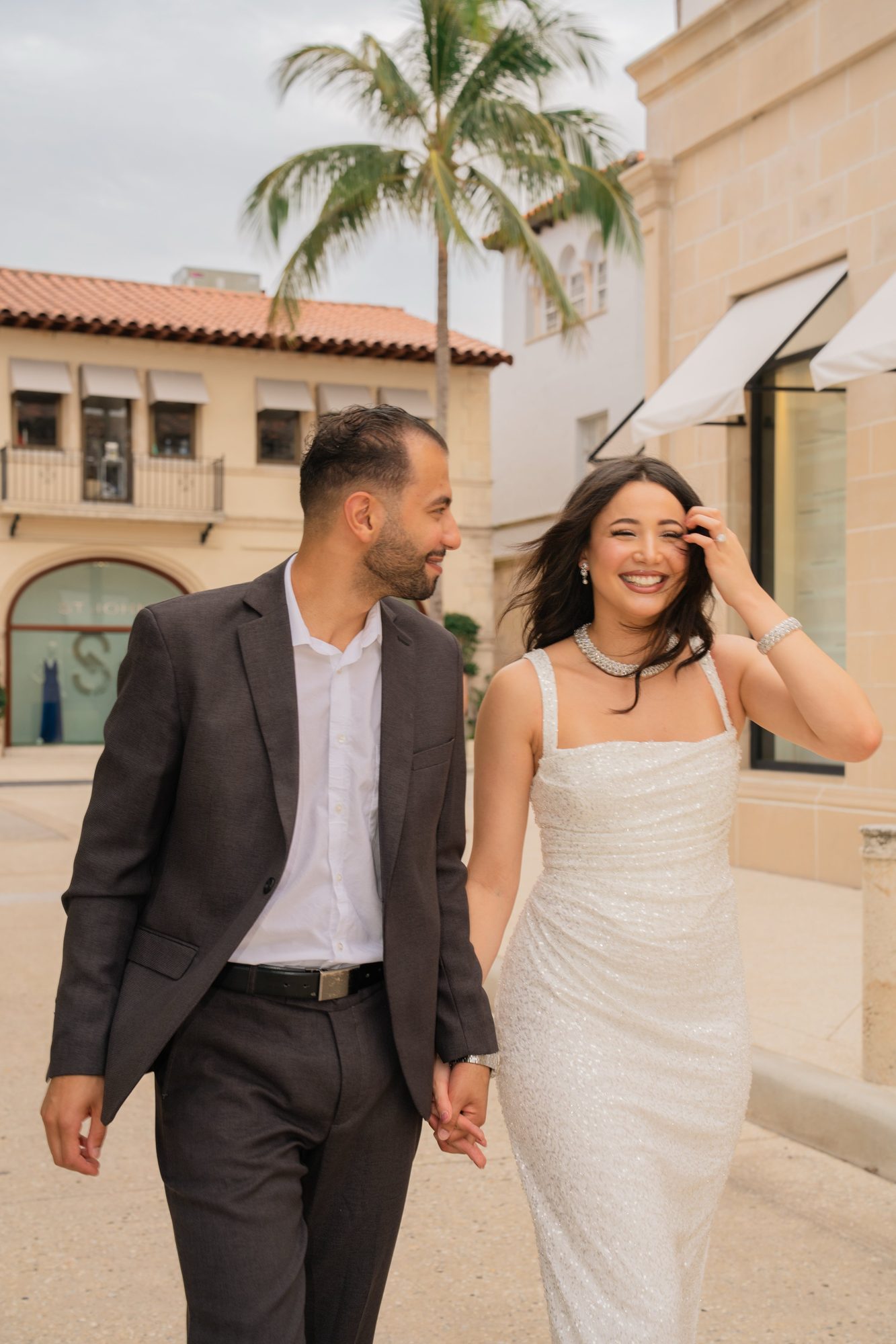 Couple walking hand in hand down a palm lined street