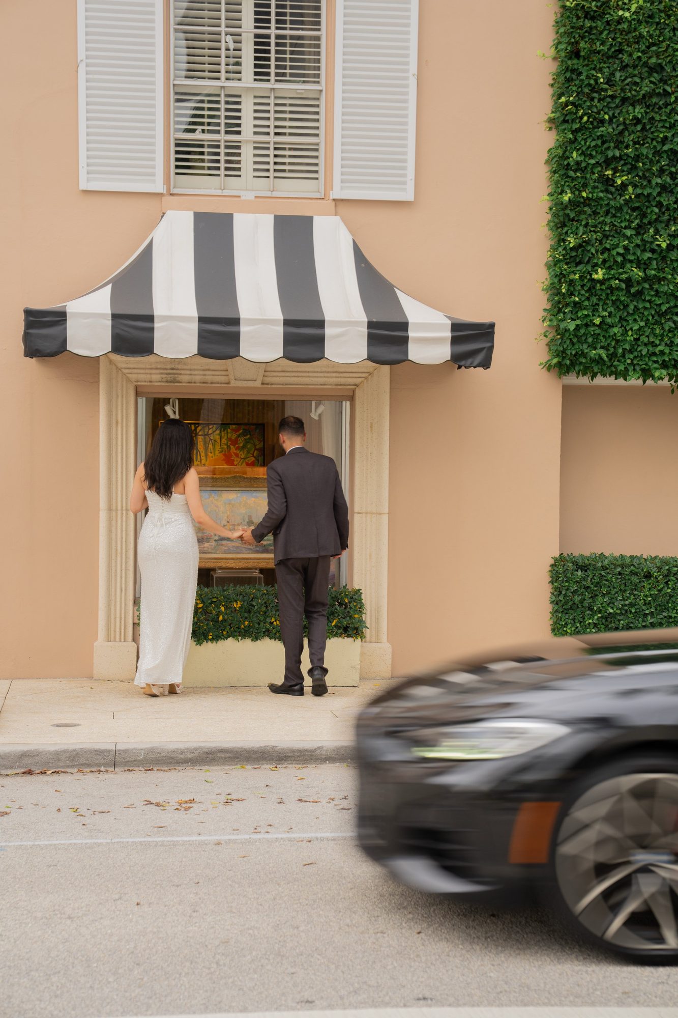 Couple walking hand in hand past a shop entrance