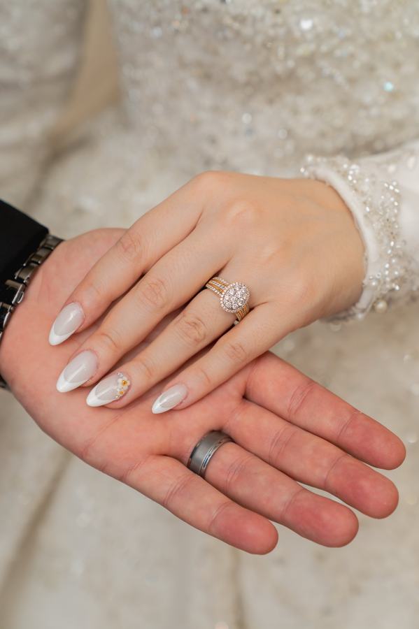 Wedding rings and boutonniere arranged close together beside the couple