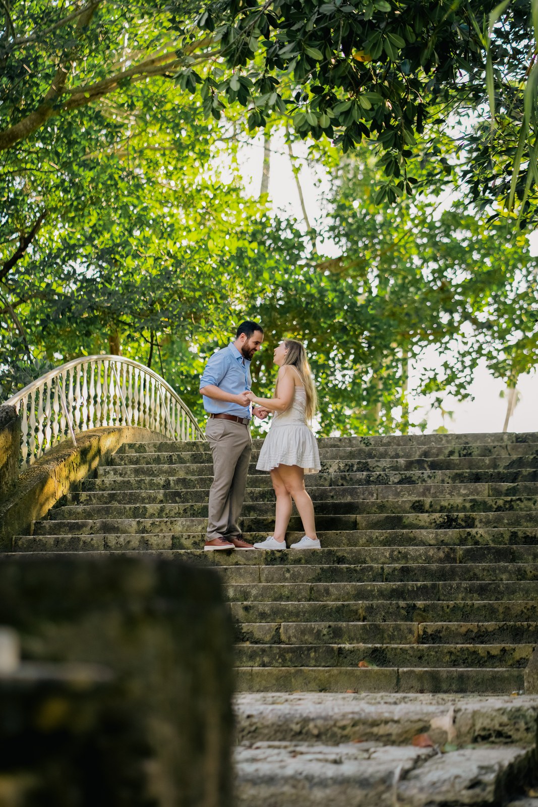 Couple sharing a kiss on stone garden steps surrounded by greenery