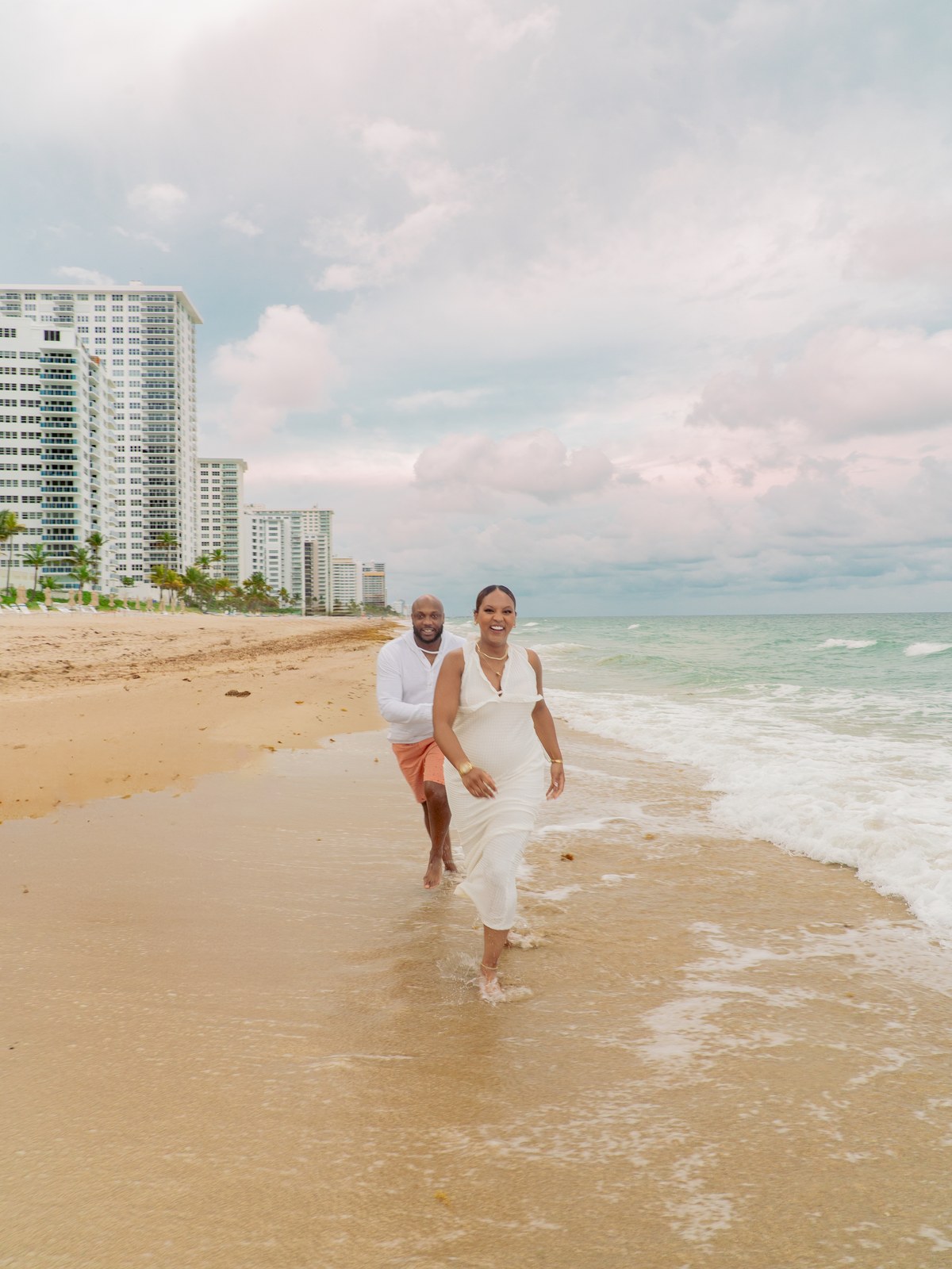 Couple walking along the beach with the coastline behind them