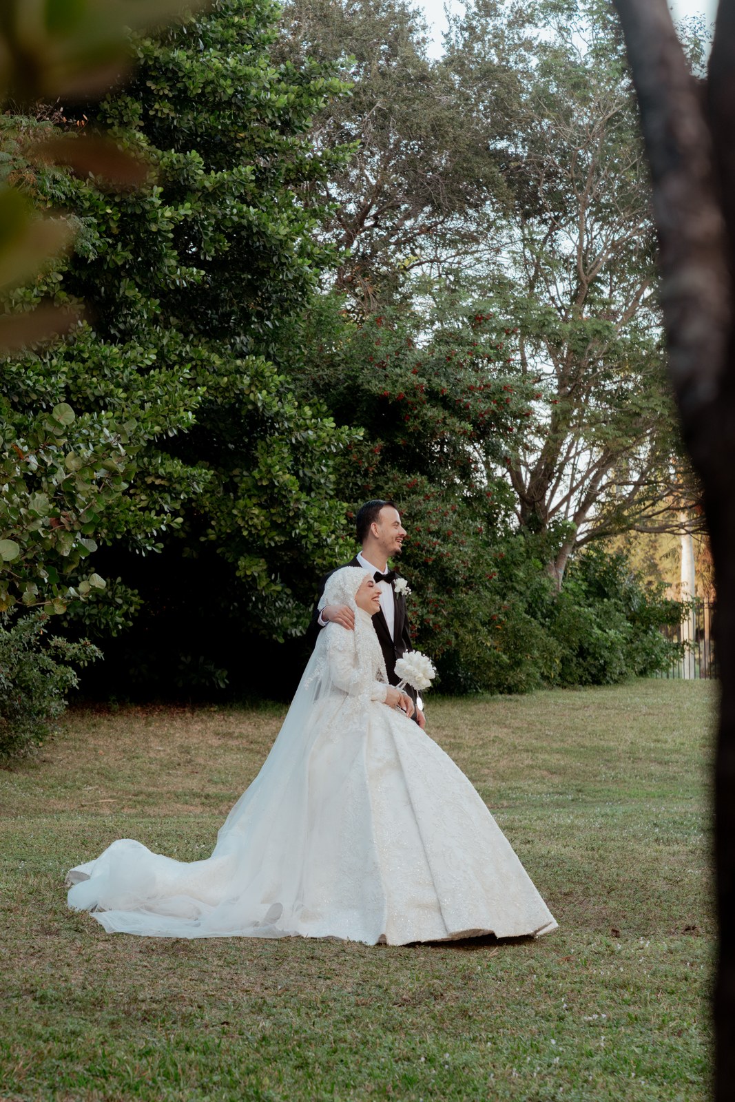 Bride in a full lace ballgown holding her bouquet in a garden