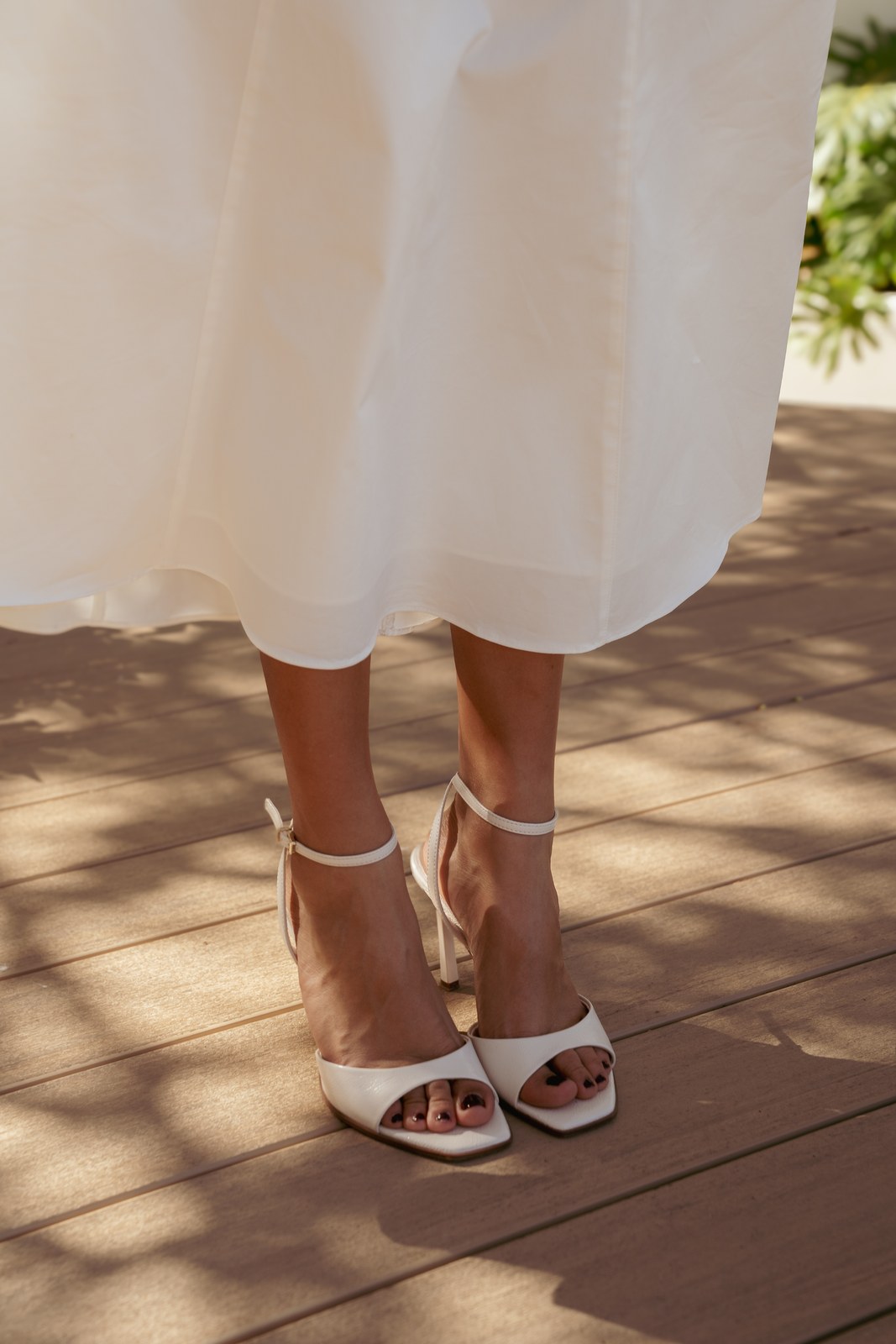 Close view of the bride’s strappy heels on a sunlit deck