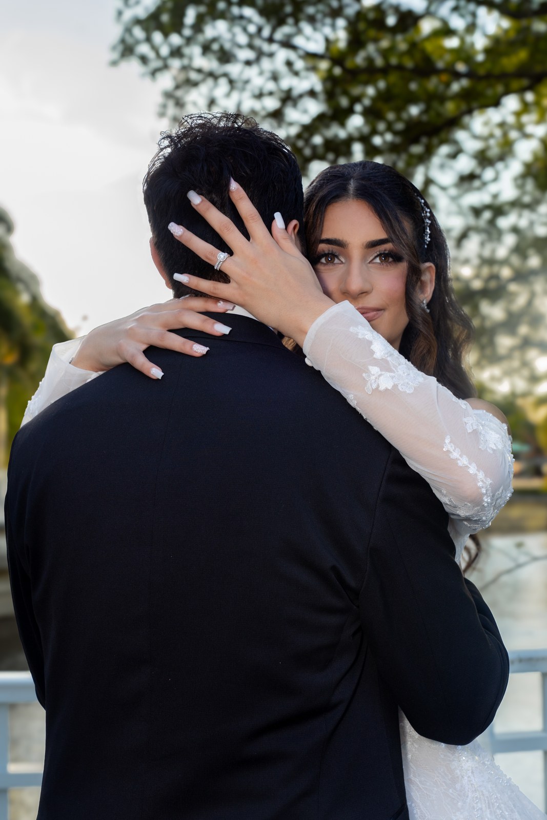 Bride resting her hands on the groom’s back in a close embrace at golden hour