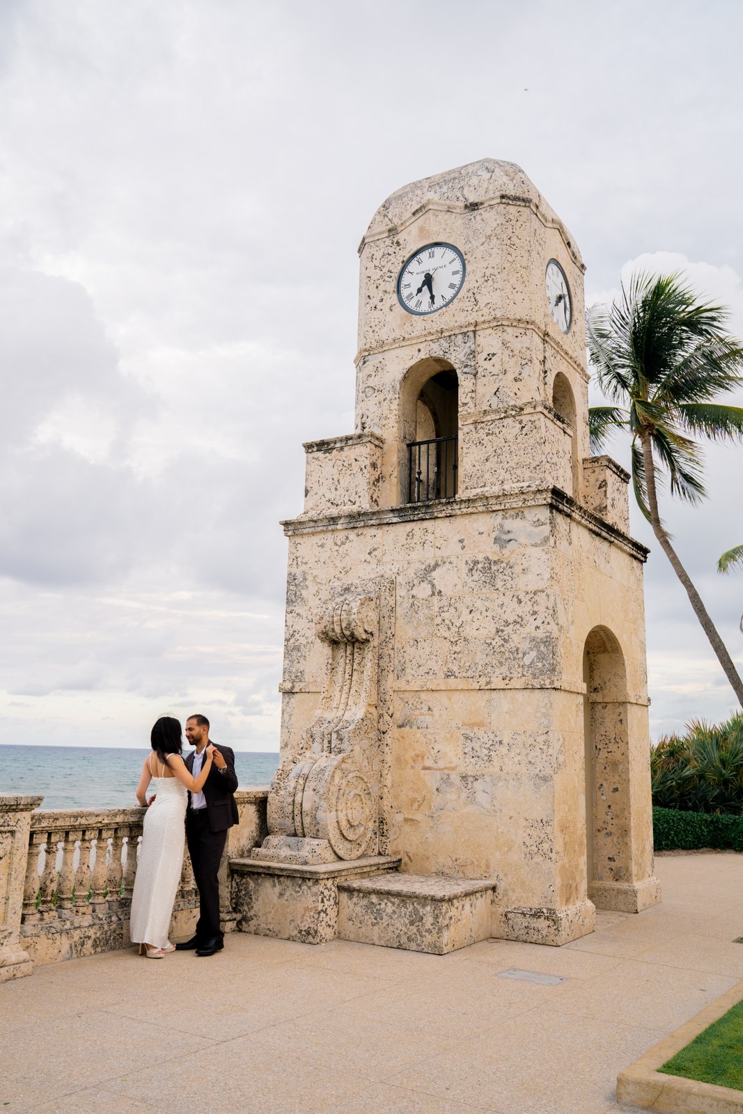 Bride and groom beside a clock tower on a Palm Beach avenue